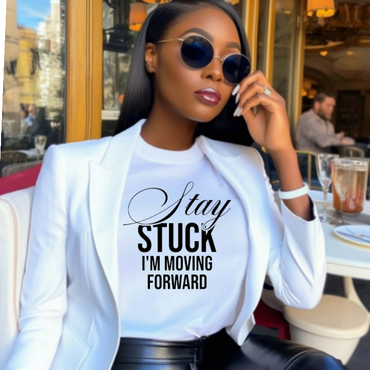 Woman wearing a white blazer over a graphic t-shirt with text, sitting outdoors.